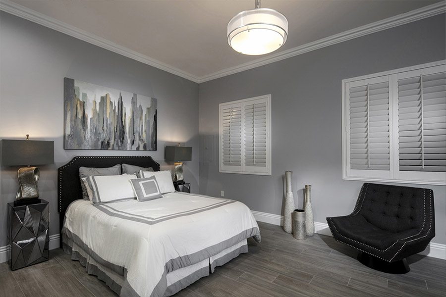  Closed white Polywood shutters on windows in a gray bedroom